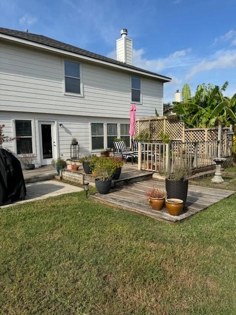 rear view of property featuring a lawn and a deck