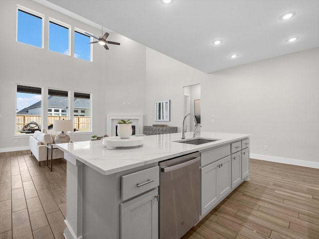 kitchen with white cabinetry, sink, a kitchen island with sink, ceiling fan, and stainless steel dishwasher