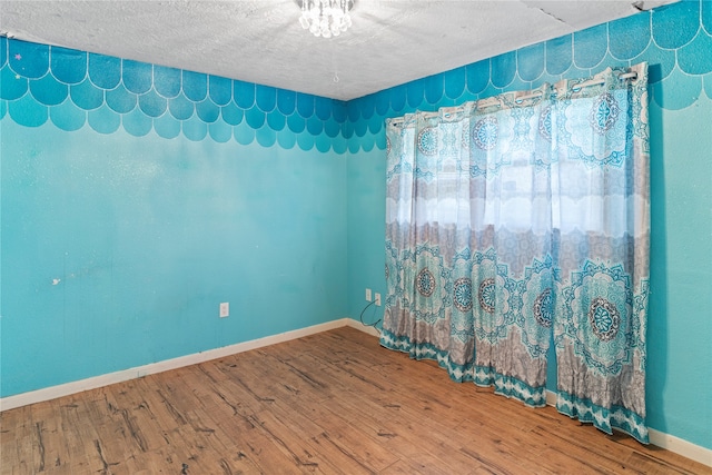 empty room with wood-type flooring and a textured ceiling