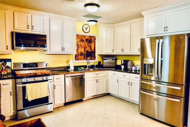 kitchen with white cabinetry, appliances with stainless steel finishes, sink, and a textured ceiling