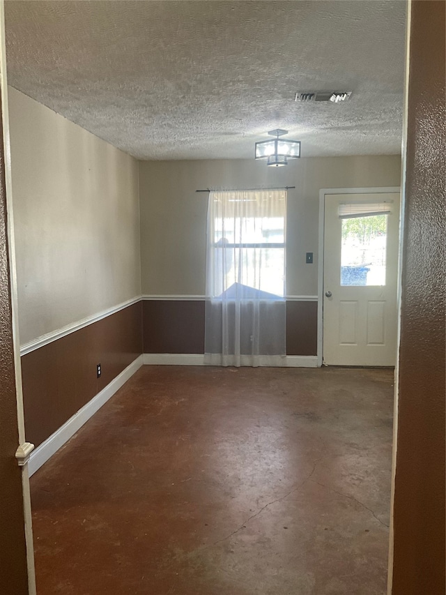 interior space with a textured ceiling and concrete flooring