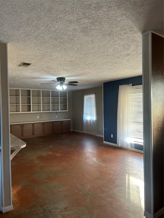 unfurnished living room with concrete flooring, a textured ceiling, and ceiling fan