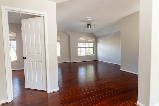 empty room featuring lofted ceiling, dark hardwood / wood-style floors, ceiling fan, and plenty of natural light