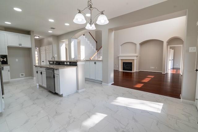 kitchen with white cabinets, dishwasher, light wood-type flooring, decorative light fixtures, and a center island with sink