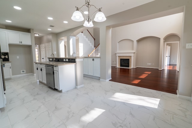 kitchen featuring pendant lighting, stainless steel dishwasher, a center island with sink, white cabinetry, and light wood-type flooring