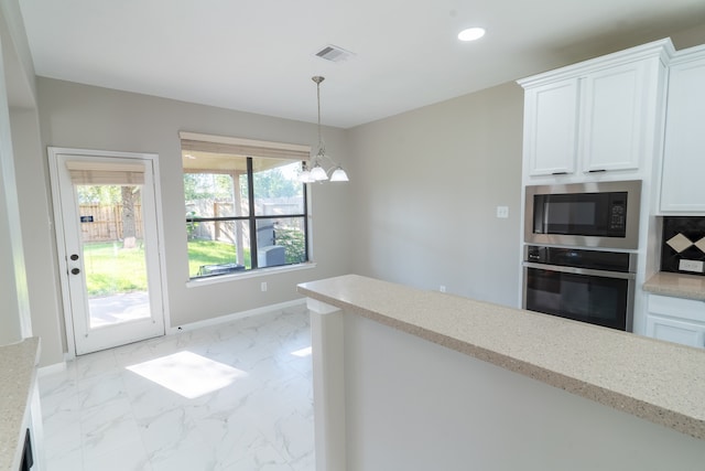 kitchen with white cabinets, black microwave, stainless steel oven, an inviting chandelier, and decorative light fixtures