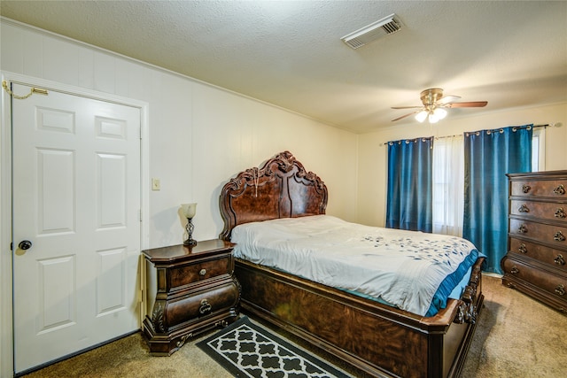 carpeted bedroom featuring ceiling fan and a textured ceiling