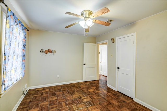 unfurnished room with dark parquet flooring and ceiling fan