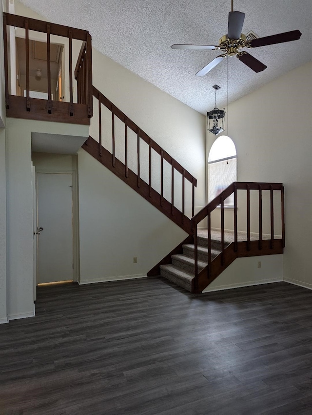 stairs featuring ceiling fan with notable chandelier, a textured ceiling, and hardwood / wood-style flooring