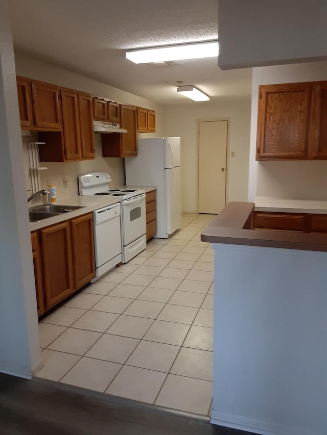 kitchen with light tile patterned flooring, a textured ceiling, sink, and white appliances