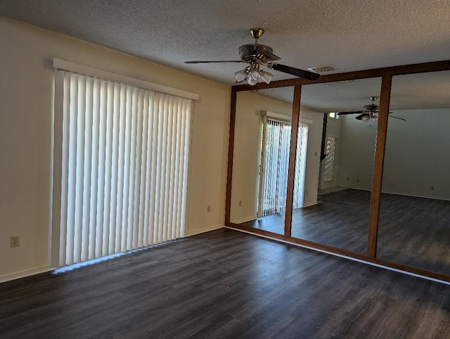 unfurnished bedroom with ceiling fan, a textured ceiling, and dark wood-type flooring