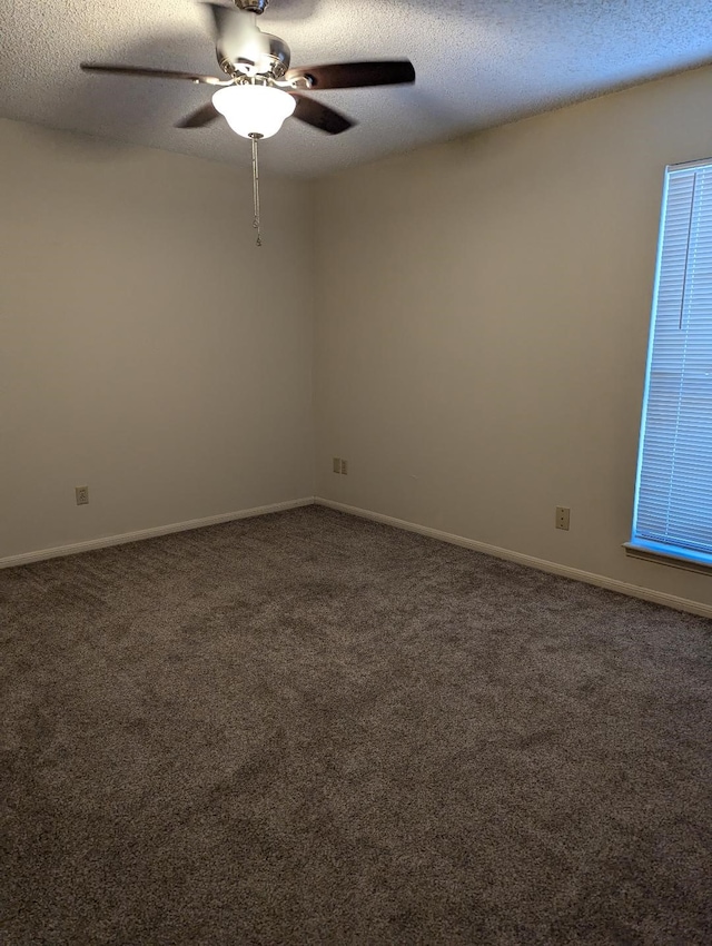 empty room with dark carpet, a textured ceiling, and ceiling fan