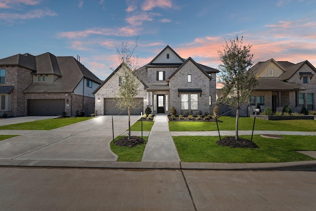 french country style house featuring a garage, driveway, a front lawn, and stone siding