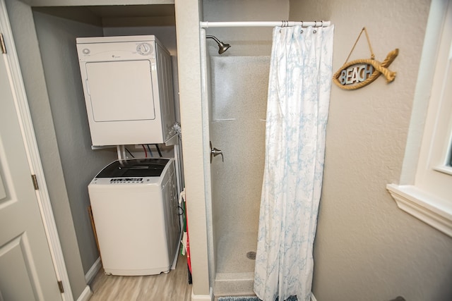 bathroom with hardwood / wood-style flooring, stacked washing maching and dryer, and a shower with curtain