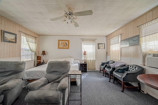 bedroom with cooling unit, wood walls, dark colored carpet, and ceiling fan