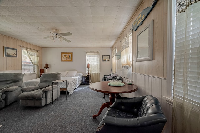 carpeted bedroom featuring wood walls and ceiling fan