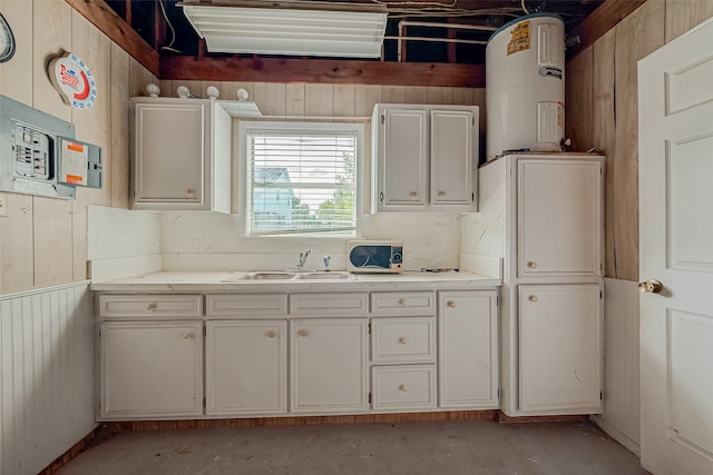 kitchen featuring wooden walls, sink, and white cabinetry