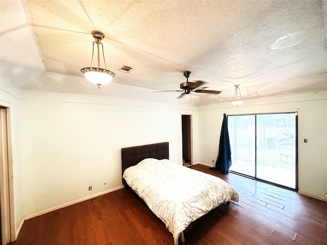 bedroom featuring ceiling fan, a textured ceiling, dark hardwood / wood-style floors, and access to outside