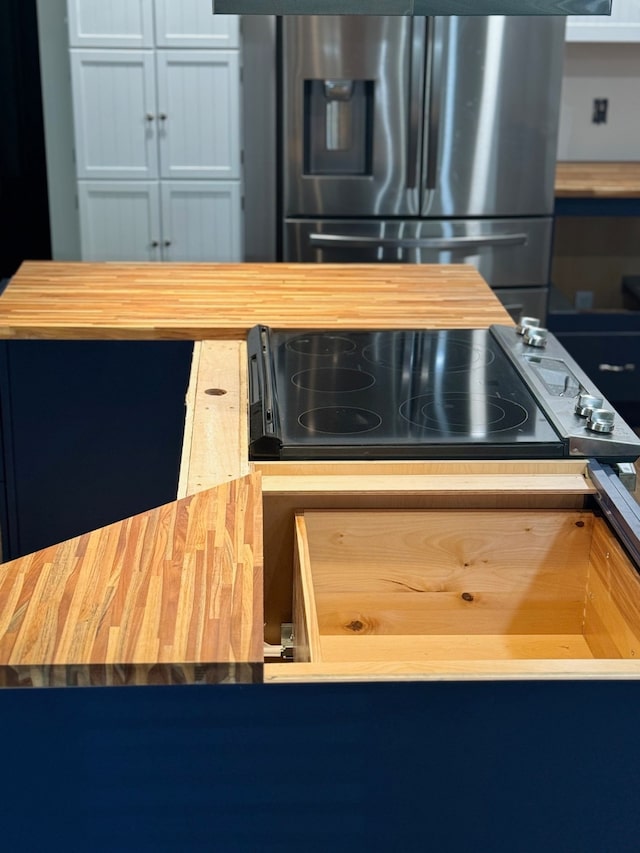 kitchen featuring cooktop, stainless steel fridge, and butcher block countertops