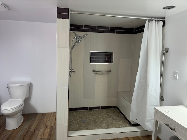 bathroom featuring wood-type flooring, toilet, vanity, and curtained shower