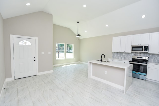 kitchen featuring appliances with stainless steel finishes, white cabinets, ceiling fan, a kitchen island with sink, and sink