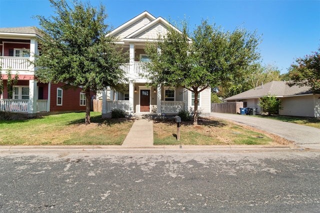 view of front of home with a balcony, a front yard, and covered porch