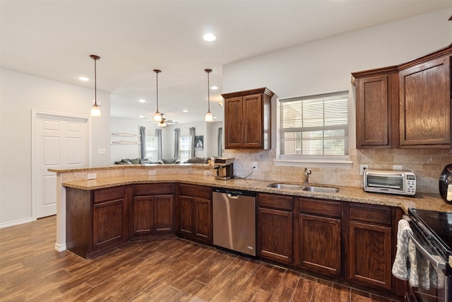 kitchen with hanging light fixtures, kitchen peninsula, sink, appliances with stainless steel finishes, and dark hardwood / wood-style flooring