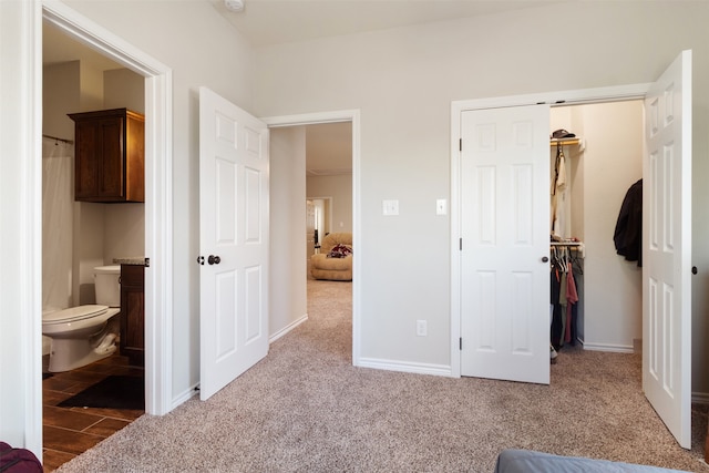 carpeted bedroom with ensuite bath, a walk in closet, and a closet