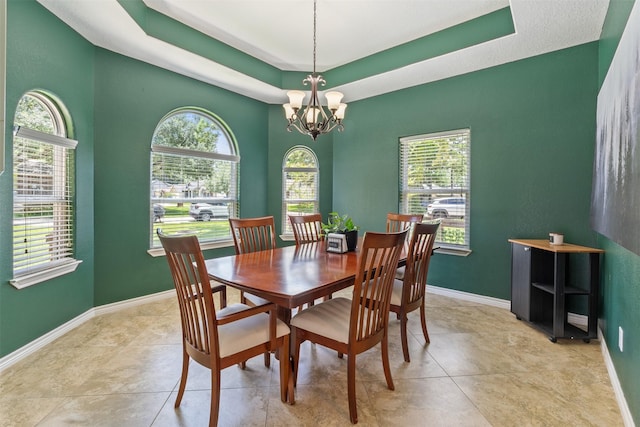 tiled dining space featuring a tray ceiling and a notable chandelier