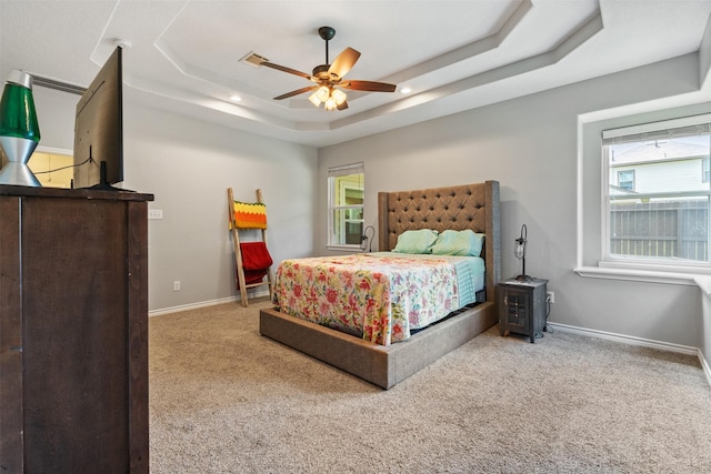 carpeted bedroom featuring ceiling fan and a tray ceiling