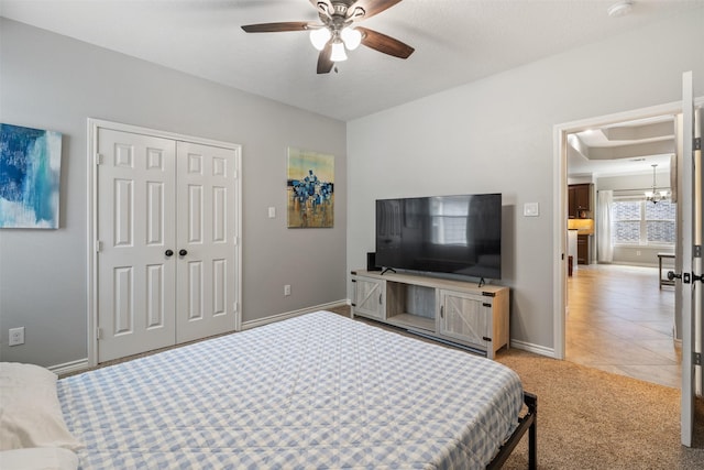 carpeted bedroom with a closet and ceiling fan with notable chandelier