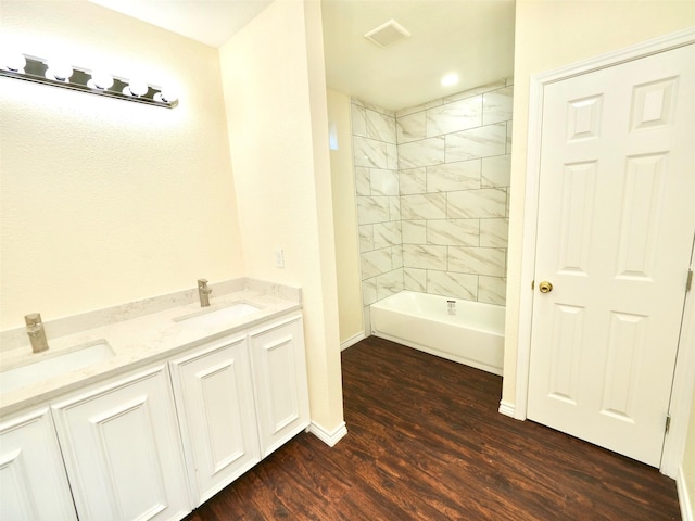 bathroom with wood finished floors, baseboards,  shower combination, and double vanity