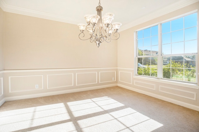 carpeted spare room featuring ornamental molding and a chandelier