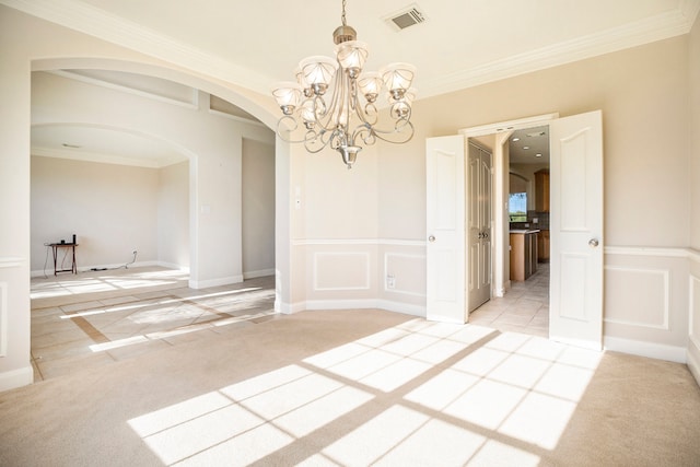 spare room featuring carpet flooring, an inviting chandelier, and ornamental molding