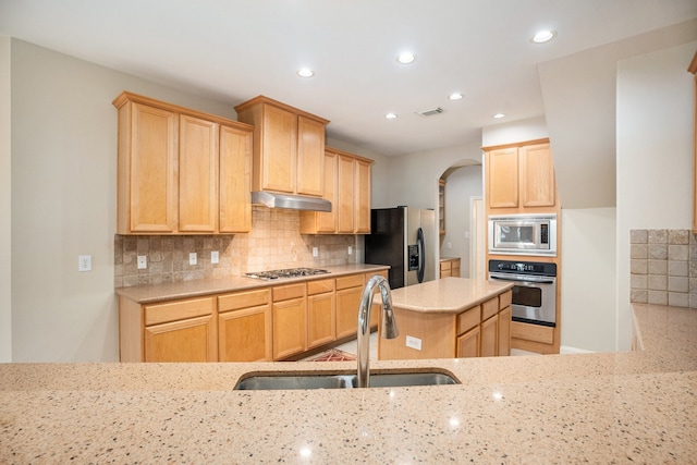 kitchen with light stone counters, sink, backsplash, light brown cabinets, and appliances with stainless steel finishes