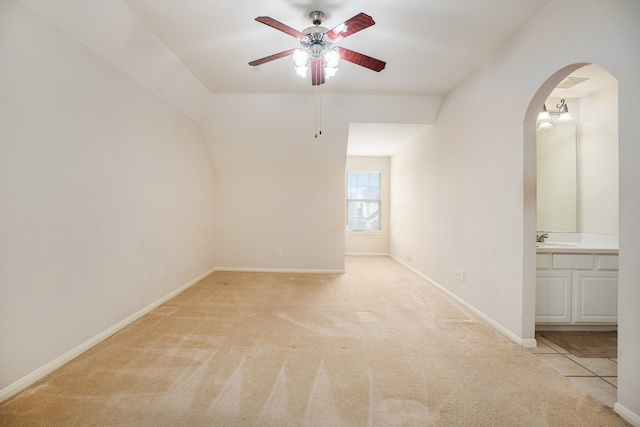 carpeted spare room featuring ceiling fan, vaulted ceiling, and sink