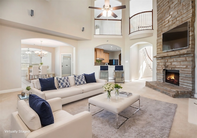 carpeted living room with an inviting chandelier, a fireplace, and a high ceiling