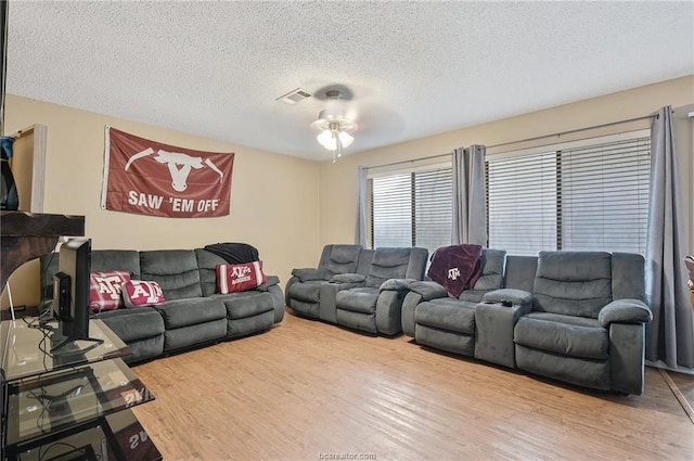 living room featuring a textured ceiling, ceiling fan, and hardwood / wood-style flooring