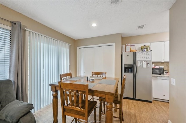 dining room featuring light wood-type flooring and a textured ceiling