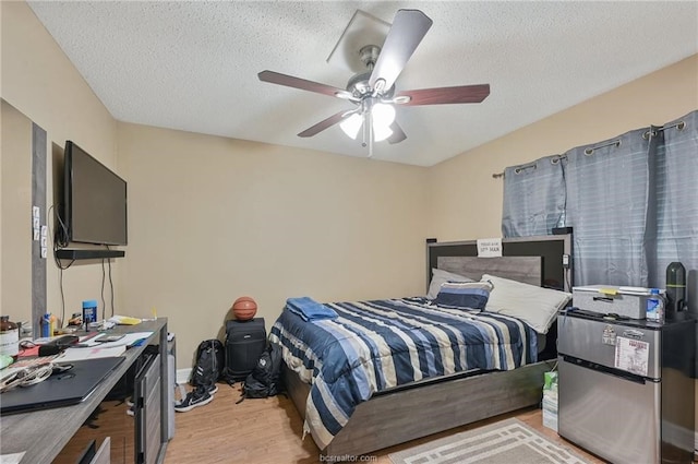 bedroom featuring light hardwood / wood-style floors, ceiling fan, and a textured ceiling