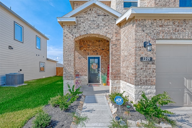 property entrance with central AC unit, a garage, and a yard