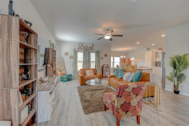 living room featuring ceiling fan with notable chandelier and light wood-type flooring