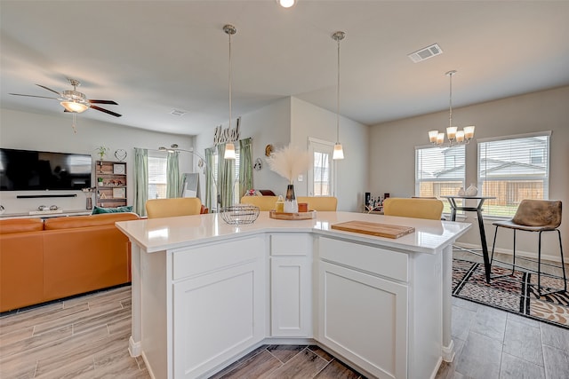 kitchen with light hardwood / wood-style flooring, white cabinets, a center island, and decorative light fixtures