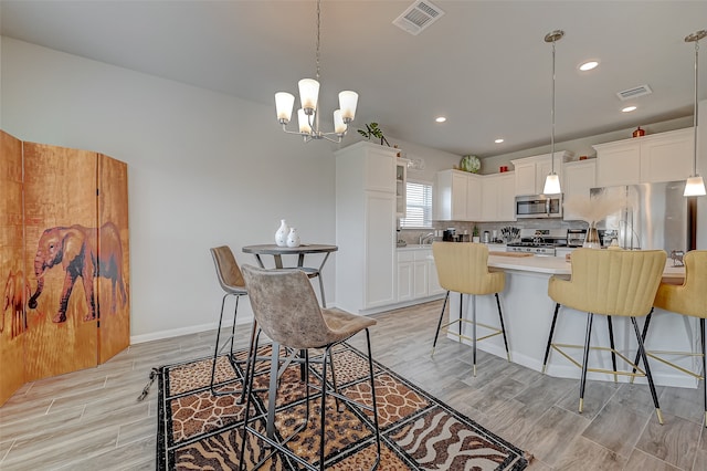 kitchen with pendant lighting, a chandelier, white cabinets, a kitchen island, and stainless steel appliances