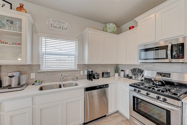 kitchen with white cabinets, stainless steel appliances, backsplash, and sink