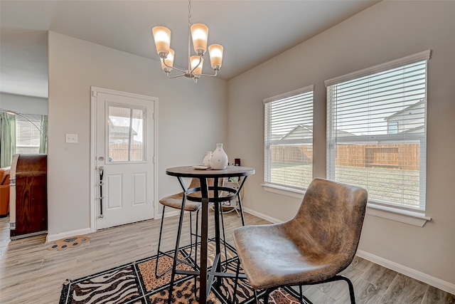 dining space with a healthy amount of sunlight, light hardwood / wood-style flooring, and a notable chandelier