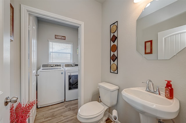 bathroom featuring washer and clothes dryer, hardwood / wood-style floors, toilet, and sink