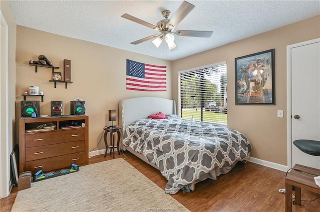 bedroom with ceiling fan, hardwood / wood-style flooring, and a textured ceiling