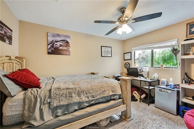 bedroom with a textured ceiling, stainless steel fridge, ceiling fan, and light colored carpet