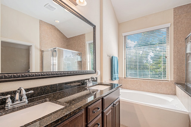 bathroom featuring vaulted ceiling, independent shower and bath, and vanity